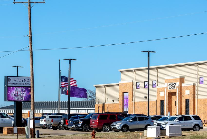 A solid purple flag flies alongside the U.S. and Texas flags outside of LaPoynor School, part of LaPoynor ISD, in LaRue on Jan. 18, 2024.