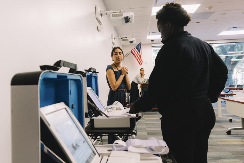 On the left, Tania Cora, Education Coordinator of Harris County Clerk’s Office Elections, provides guidance on how to use a voting machine at DeBakey High School Civics Club’s voter education conference in Houston, on Friday, April 5, 2024.