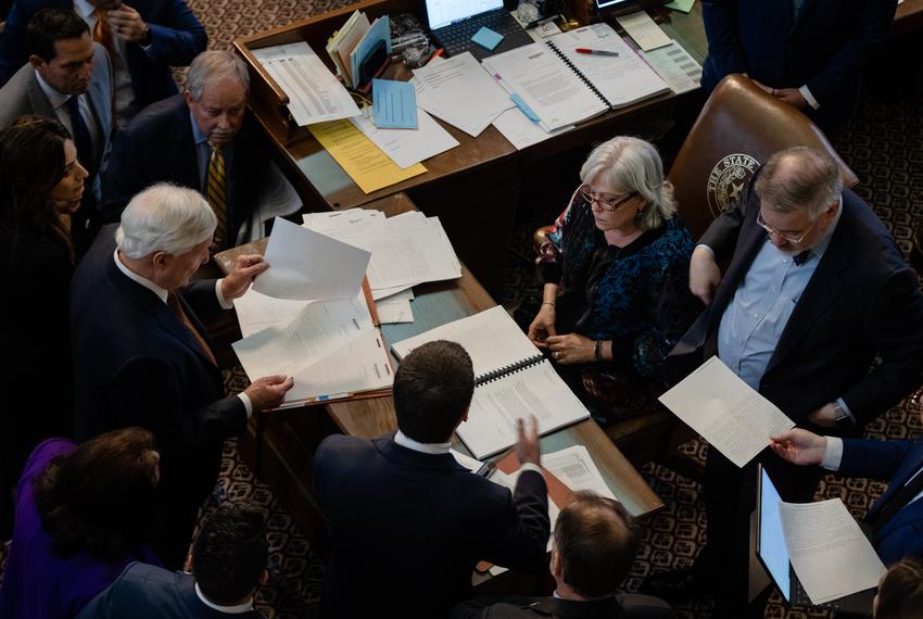 Lawmakers gather around House Parliamentarian Sharon Carter during budget discussions on the House floor of the state Capitol in Austin on April 6, 2023. 