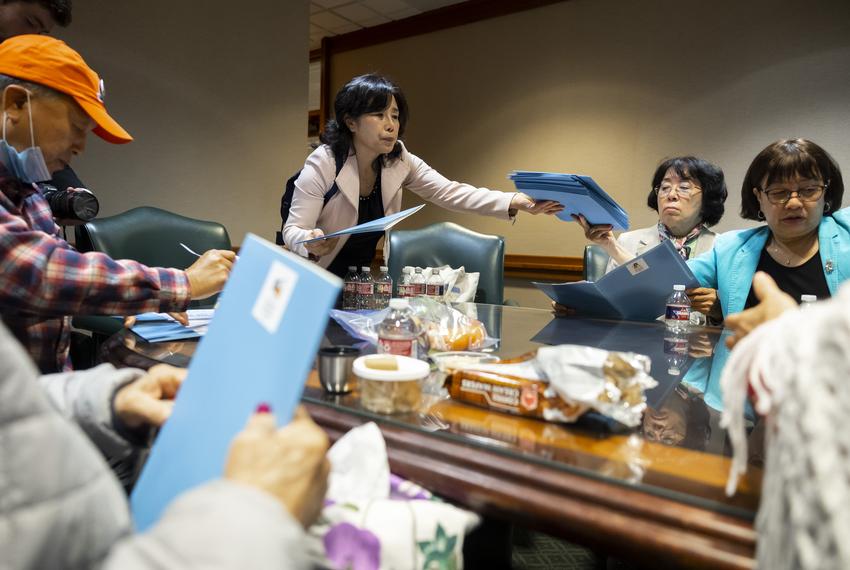 Woori Juntos Service Coordinator Si Hwa Gi hands out information packets about speaking with lawmakers on Tuesday, April 25, 2023.