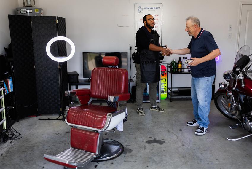 Johnson, 31, Johnathan Bladez Men’s Hair Care owner, shakes hands with regular customer David Thibodeau, pictured in Cleveland on March 12, 2024. Johnathan explained that he shares a special bond with his customers, who often feel like “brothers,” he said.