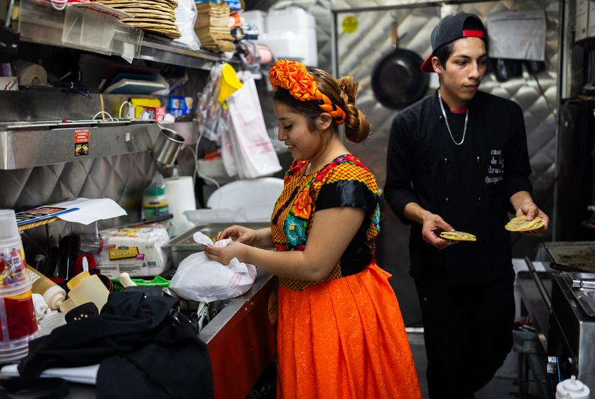 Pamela Vasquez, dressed in traditional Oaxacan clothes, left, 17, and Brayan Sibaja, 18, prepare orders at Tlayudas House food truck on March 8, 2024, in Cleveland.