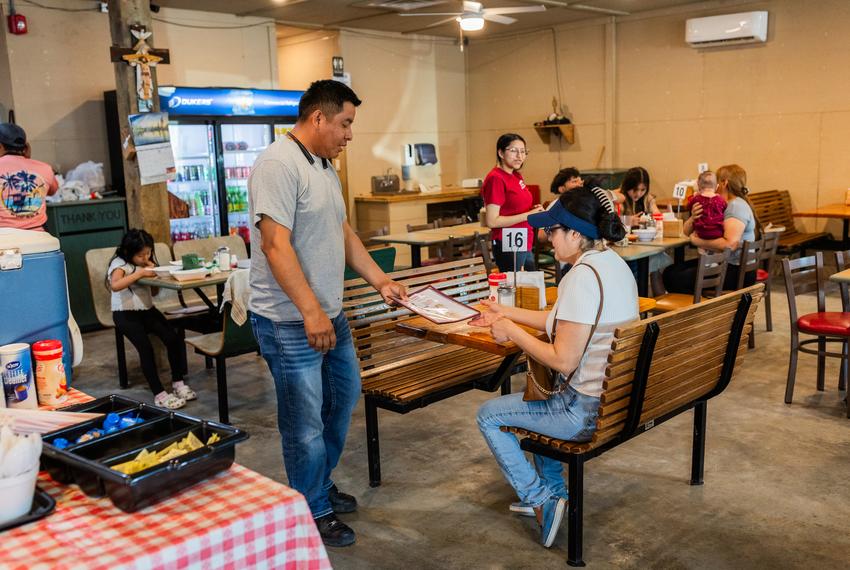 Lorenzo, owner of Barbacoa El Maguey, provides a menu to a customer at his restaurant on Sunday, April 14, 2024, in Cleveland. “Nothing is handed to you without sacrifices,” he said.