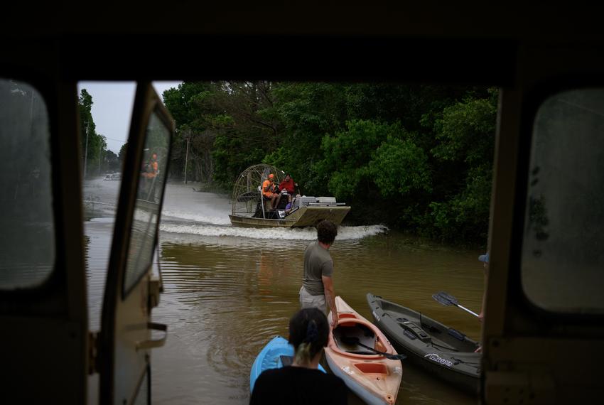 An airboat returns with rescued pets in tow as a group of people launch kayaks into floodwaters following significant rainstorms in Coldspring on May 4, 2024.