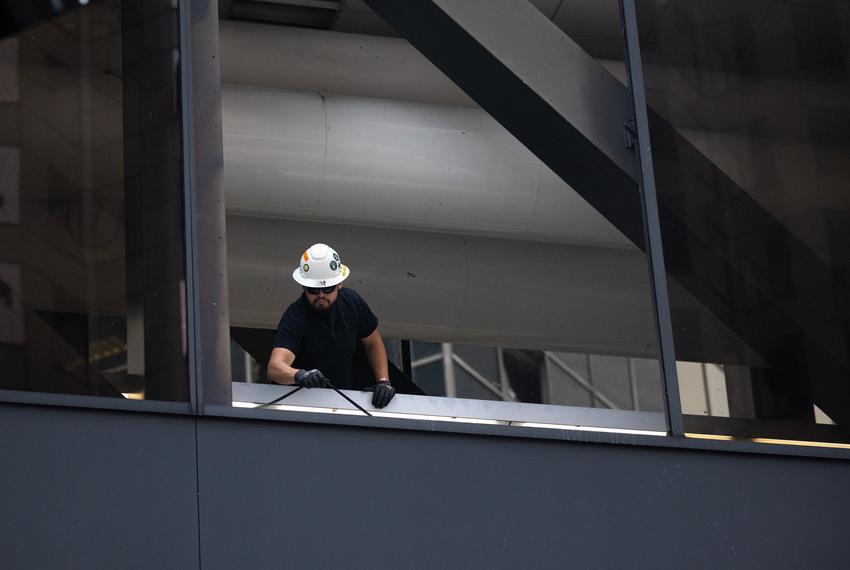 A worker clears damaged windows in the CenterPoint Energy Plaza building in downtown, Friday, May 17, 2024, in Houston. (Antranik Tavitian / Houston Landing)