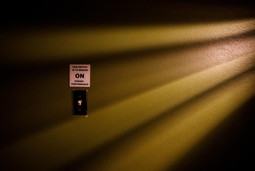 A light switch in the Paramount Theater is illuminated by light filtering through a slatted vent.