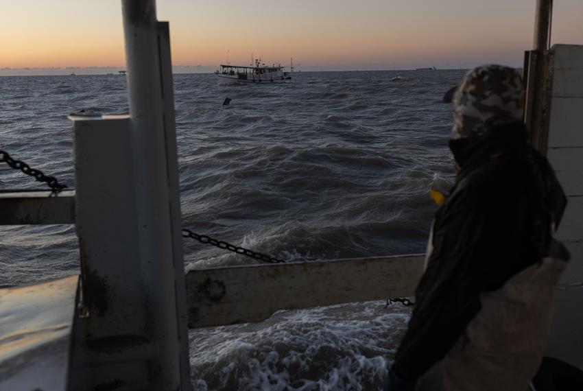 Manuel Perez watches as neighboring oyster boats maneuver around the harvesting zone in Galveston Bay, outside of Texas City, on the first day of the oyster harvesting season, on Nov. 1, 2023.