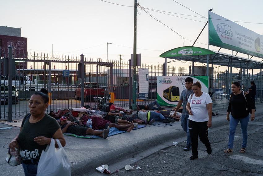 Immigrants, many from Venezuela, sleep by the entrance of an international bridge that separates Ciudad Juárez from El Paso, Texas, as local residents walk by. Some of them were waiting in the border city while trying to get an appointment to enter the U.S. using the government app CBP One.