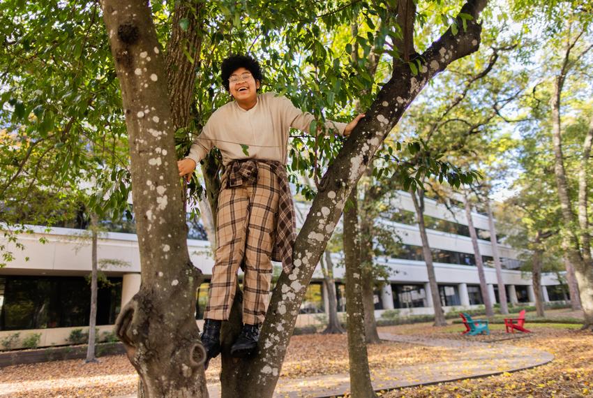 Former Mayde Creek High School student Kadence Carter, 17, is all smiles as he playfully climbs a tree while spending time at his father’s workplace on Dec. 8, 2023, in Houston.