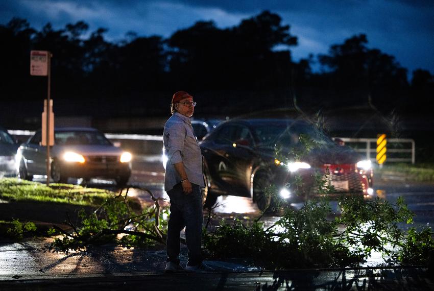 A man stands by a fallen branch blocks TC Jester Blvd. heading south because a large tree is impeding the roadway after a storm, Thursday, May 16, 2024, in Houston. (Marie D. De Jesús / Houston Landing)