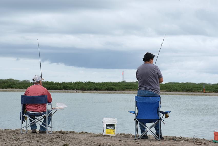 People fish in water connected to the Brownsville Ship Channel.