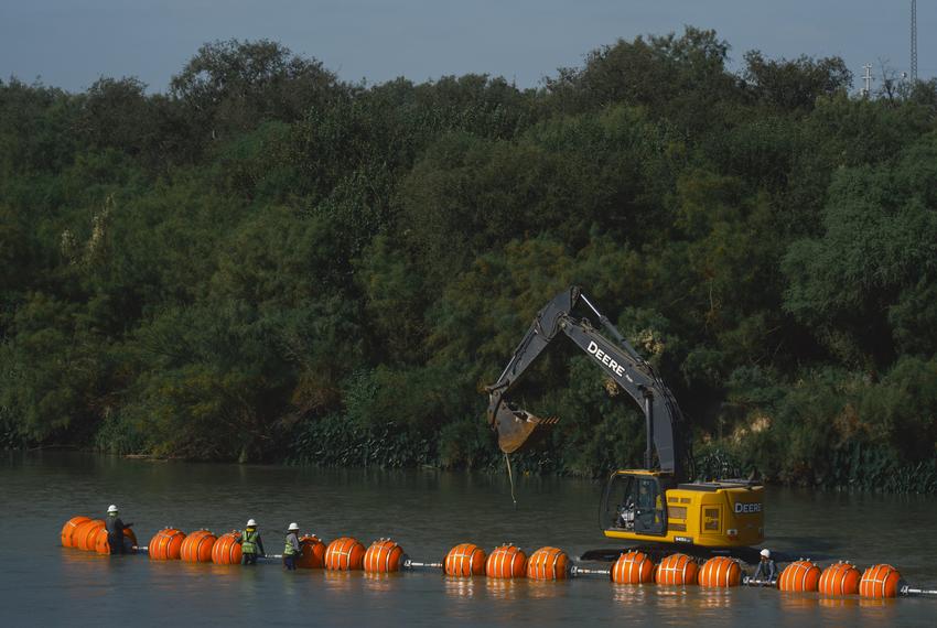 Workers construct a string of buoys which is being deployed to prevent migrants from swimming across the Rio Grande in Eagle Pass on July 14, 2023.