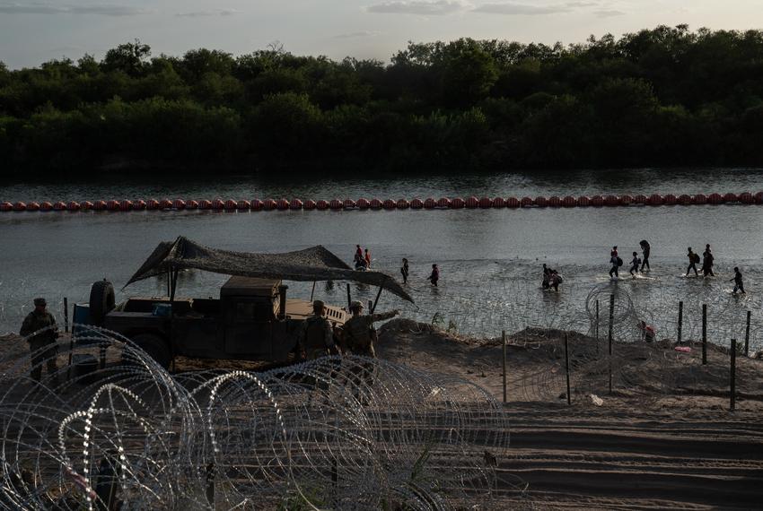 Migrants walk along the Rio Grande passed the recently installed buoys in Eagle Pass, Texas on July 29, 2023. As there is concertina wire installed along the Urbina’s property, migrants are told to walk to the end of the property. Many make that walk which can be difficult to do through slippery rocks in the water, the current and the inclined river bank, while some find spots through the concertina wire and manage to get through.
Verónica G. Cárdenas for The Texas Tribune