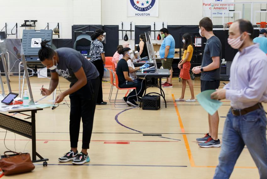 Voters check in with poll workers behind glass and cast ballots in booths spread apart in the gymnasium at the Metropolitan Multi-Service Center for the delayed primary runoff election in Houston, on July 14, 2020.