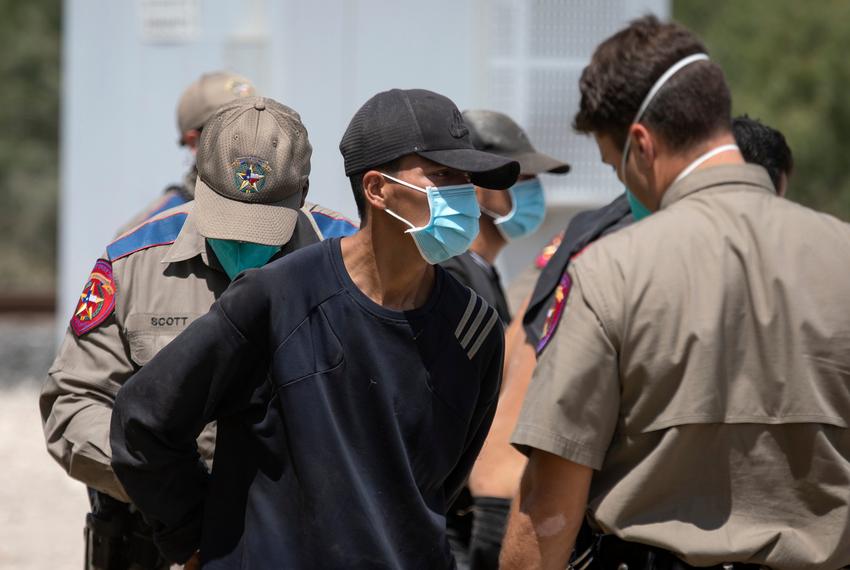 A migrant is readied to board a law enforcement van after being apprehended by Department of Public Safety officers at a train depot in Spofford on Aug. 25, 2021.