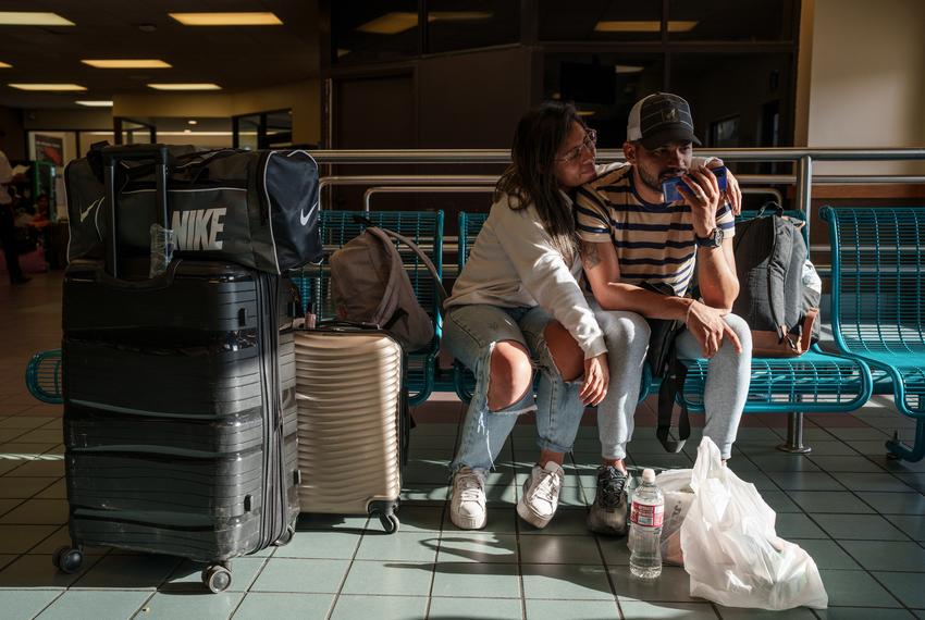 Arango and his wife, Patricia Moyano, from Bolivia, send voice messages to friends while waiting inside the Greyhound bus terminal in El Paso before traveling to Austin.