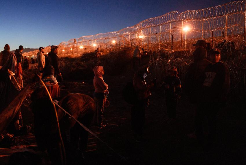 Migrants wait in Ciudad Juárez alongside a barbed-wire fence that separates the city from El Paso, Texas. Frustrated with the low numbers of people who can get appointments through the CBP One app, some of those stranded in border cities decide not to wait and instead turn themselves in to Border Patrol agents.