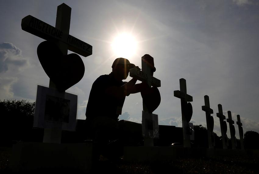 A man writes a message on a cross at a makeshift memorial left in memory of the victims killed in a shooting at Santa Fe High School in Santa Fe, on May 21, 2018.