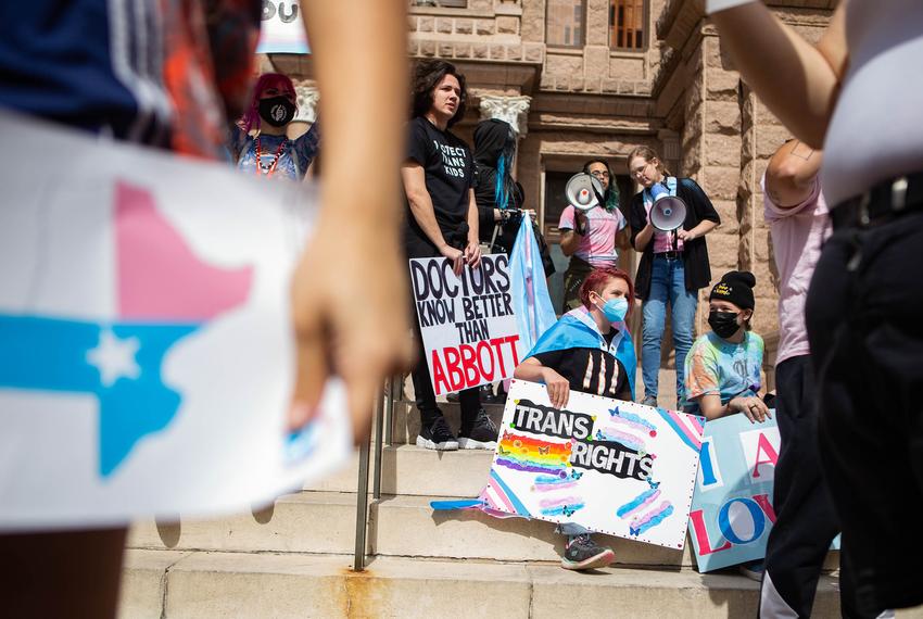 People hold signs in front of the Texas Capitol during a protest for transgender kids' rights on Tuesday, Mar. 1, 2022.