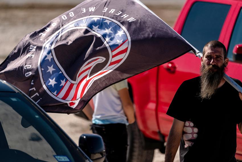 A man carries a flag with the letter 'Q' signifying the QAnon conspiracy at a "Trump Train" event in San Antonio on Nov. 1, 2020.