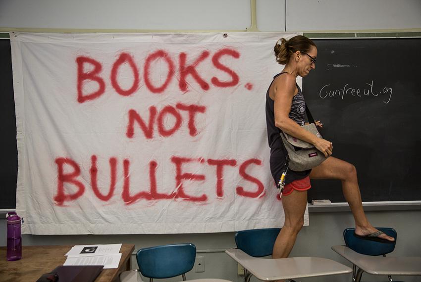 Pascale Bos, an associate professor at UT Austin, walks over desks after pinning up a "Books not bullets" sign at a peace and wellness workshop organized by Gun-Free UT and held in a UT Austin classroom on Aug. 1, 2016, the day Texas' "campus carry" law went into effect and the 50th anniversary of the mass shooting that occurred on the UT campus.